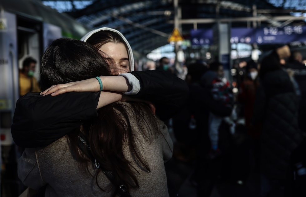 Una ragazza con gli occhi chiusi abbraccia un'altra donna, inquadrata di spalle