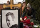 Una ragazza depone dei fiori sulla tomba, con una foto di Navalny in primo piano davanti a lei
