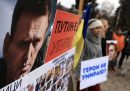 Un gruppo di persone regge dei cartelli con dei messaggi e delle foto di Navalny