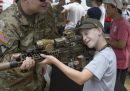 Una bambina prende la mira con un fucile aiutata da un soldato