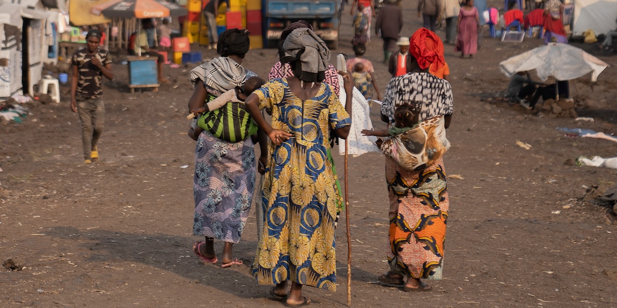 Tre donne camminano nel campo per rifugiati di Goma, nella Repubblica Democratica del Congo, 15 agosto 2024 (AP Photo/Moses Sawasawa)