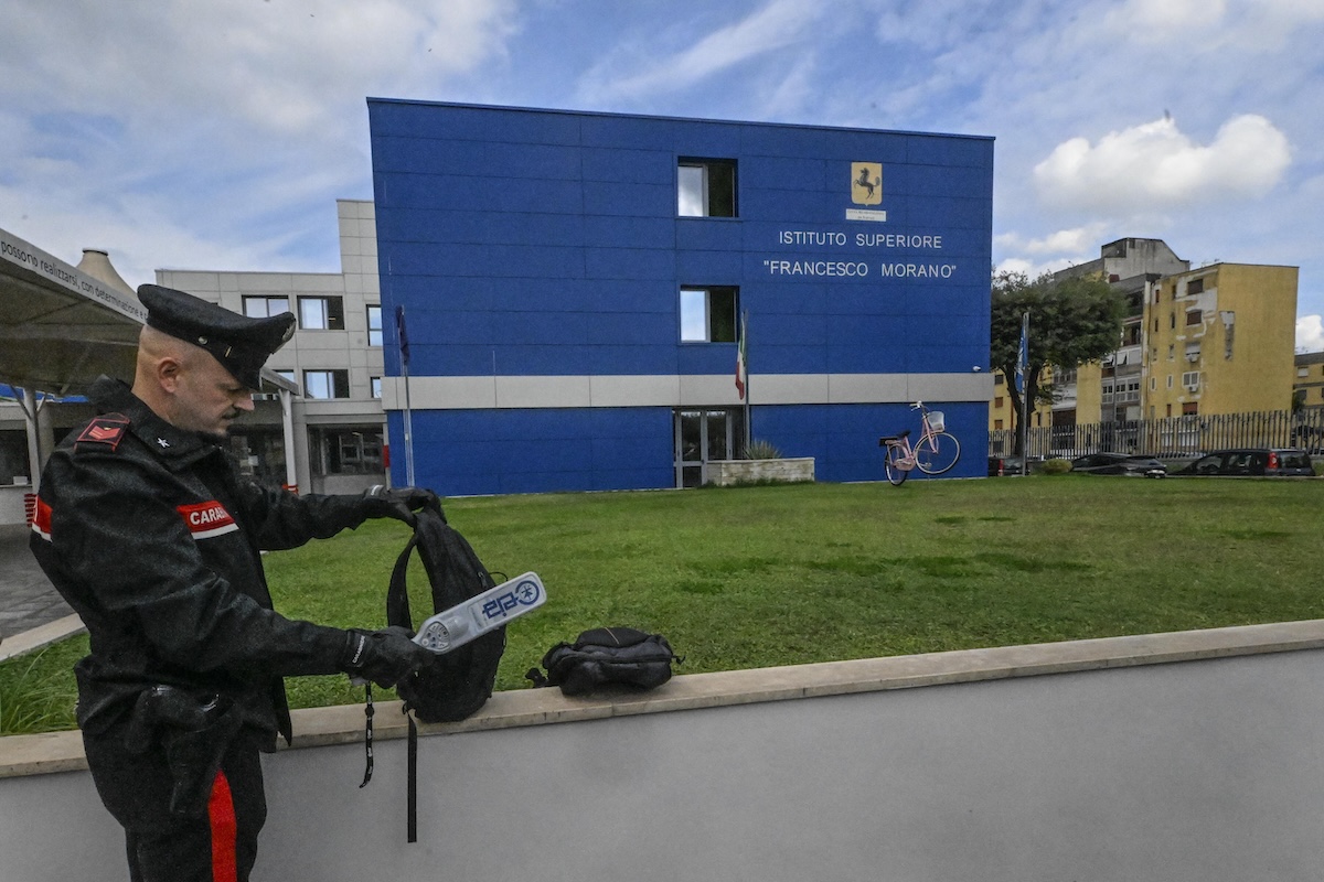 All'ingresso dell'istituto Morano del Parco Verde di Caivano, dove tre ragazzini sono stati sorpresi a scuola con dei coltelli, un carabiniere controlla gli zaini col metal detector, il 20 ottobre del 2025 (ANSA/CIRO FUSCO)