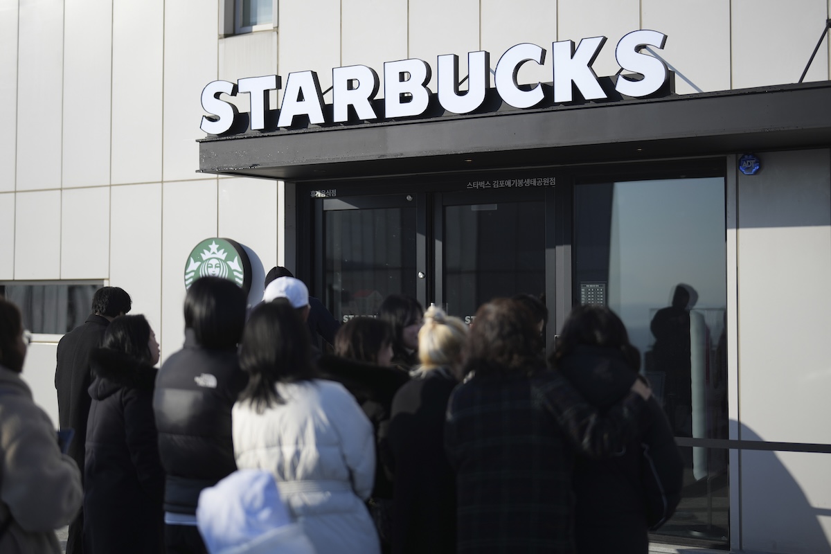 Delle persone in fila allo Starbucks dell'Aegibong Peace Ecopark a Gimpo in Corea del Sud (Lee Jin-man/AP)