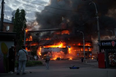 Alcuni passanti guardano l'incendio di un edificio causato da un bombardamento russo a Kiev, il 24 maggio (AP Photo/Evgeniy Maloletka)